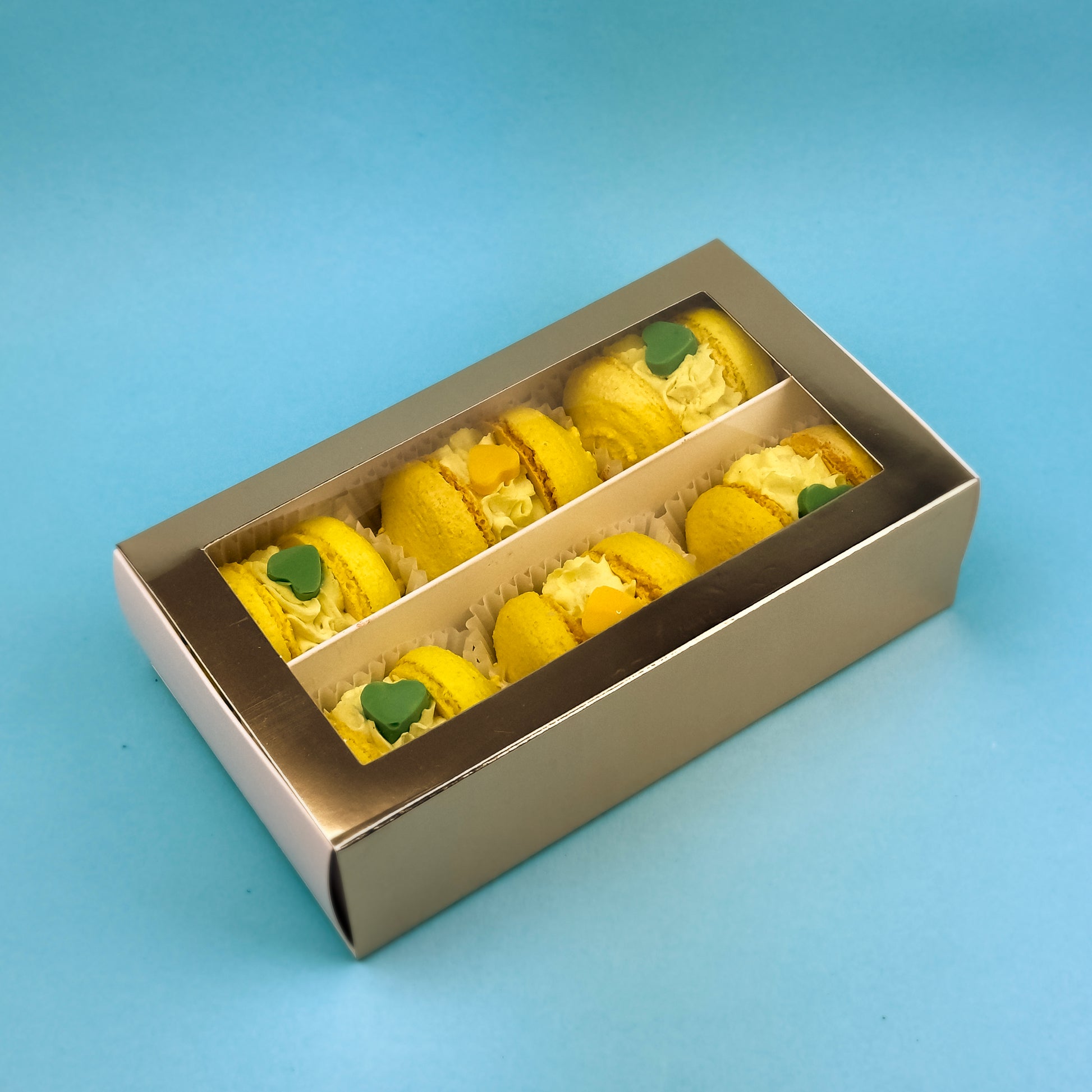 Elegant Banana-Caramel Macarons box with 6 handcrafted gluten-free macarons, premium gold packaging, and a transparent lid.