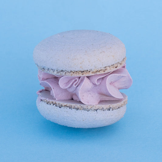 A blueberry lemon macaron with a light purple filling and crisp shell.