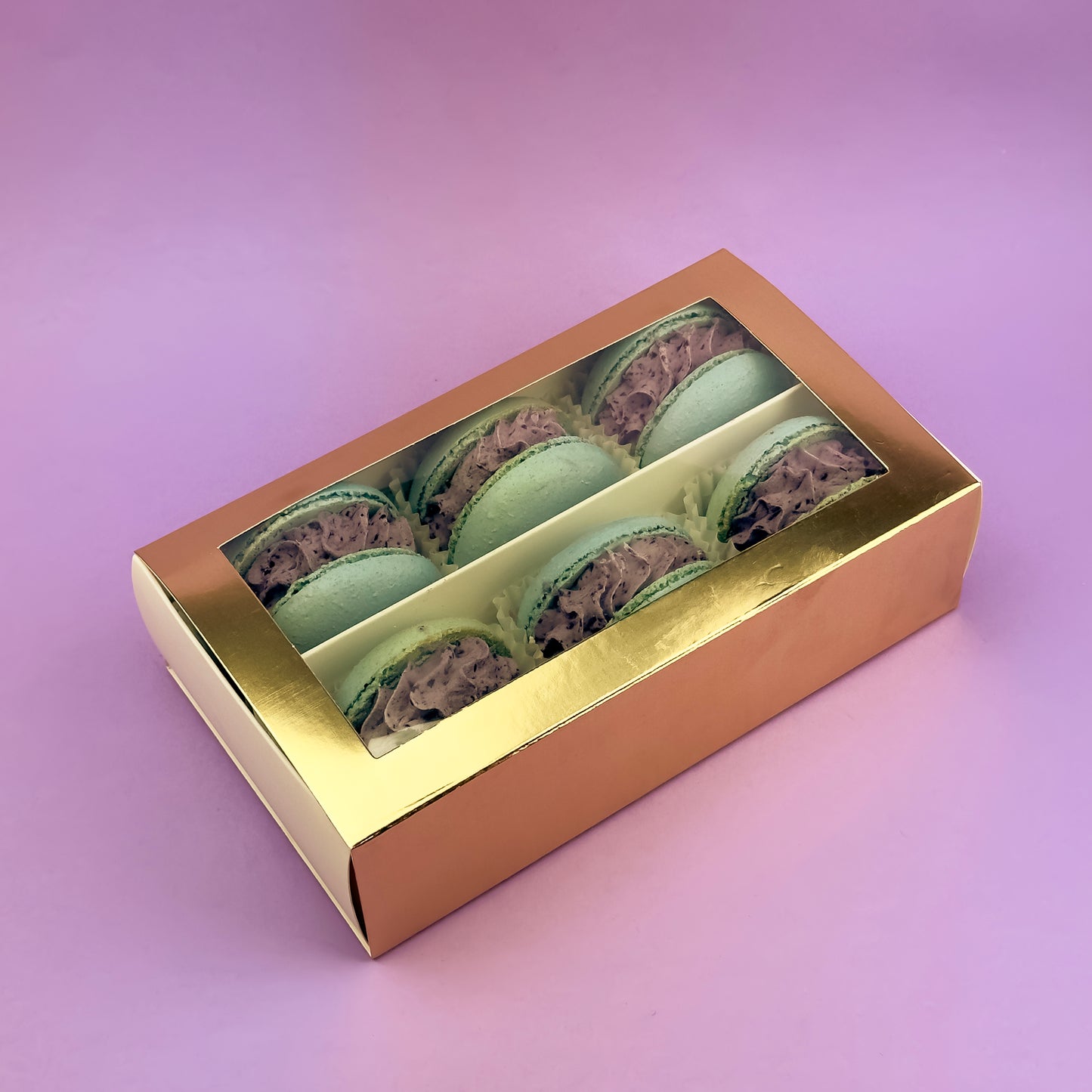 Box of 6 Blueberry Lemon Macarons in a golden-lid packaging, featuring delicate almond shells filled with blueberry puree and lemon curd, displayed on a pastel purple background.