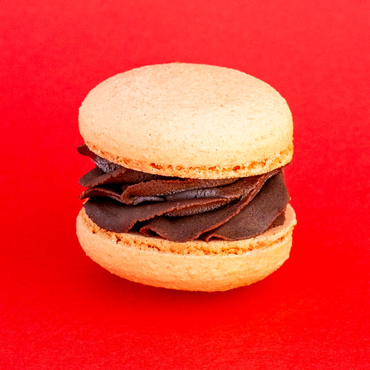 Bright orange chocolate macaron with dark chocolate filling, ideal for dessert lovers and special gifts.